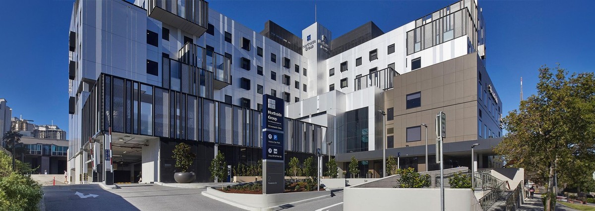 Daytime view of the Northside Group building, showcasing its modern multi-story architecture with sleek panel designs, large glass windows, and a prominent entrance sign surrounded by landscaping.